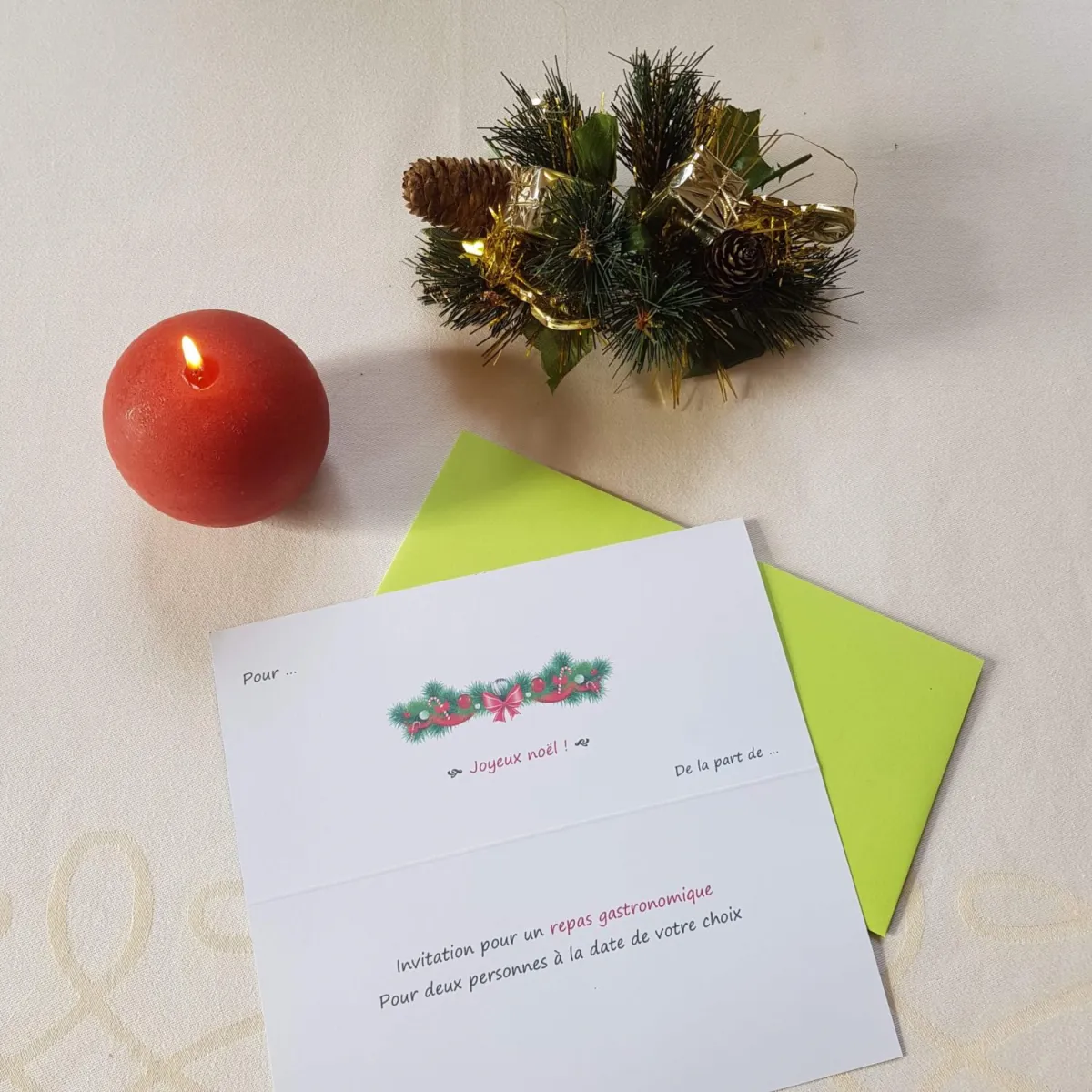 Un bon cadeau « Joyeux Noël » pour un repas gastronomique, posé près d'une bougie