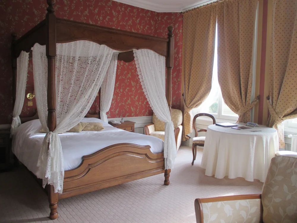 Chambre au lit à baldaquin, voilages de dentelle et rideaux dorés